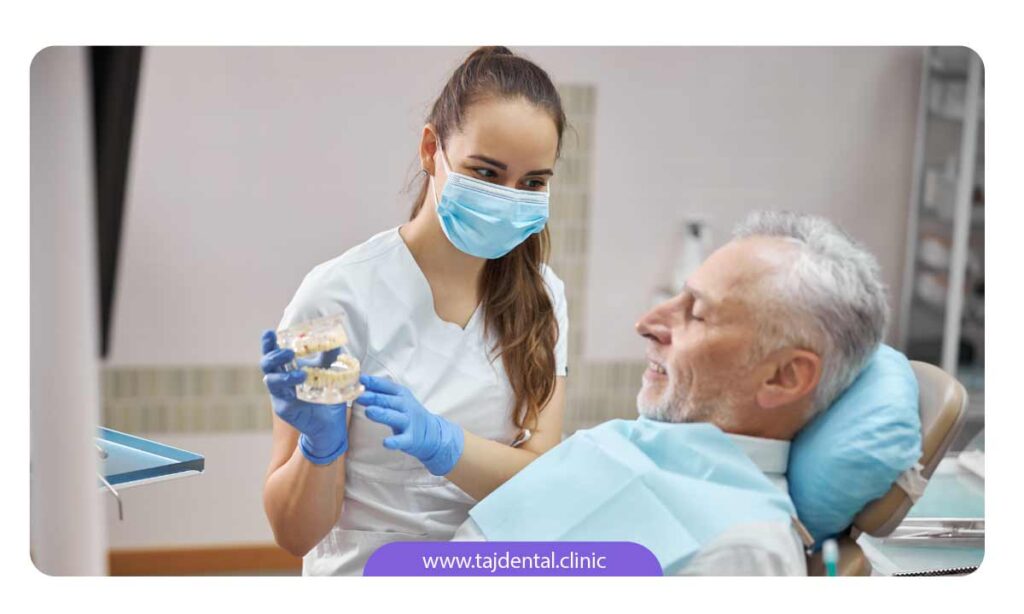 تصویر دندانپزشک در حال توضیح شرایط ایمپلنت دندان به بیمار مسن خود